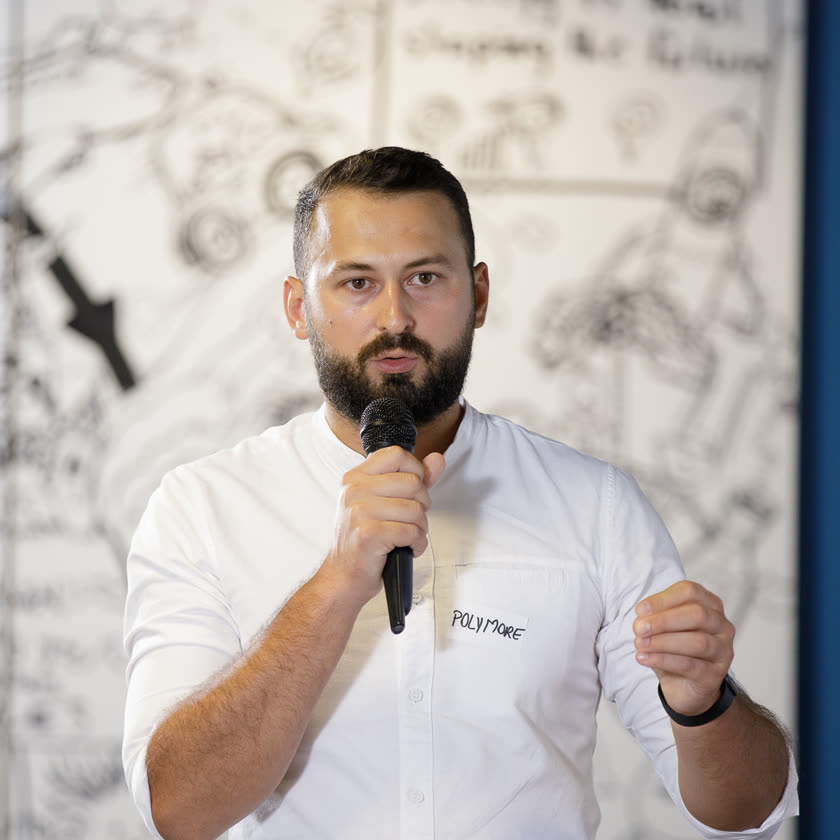 Cristian Pogan speaking at a demo day, microphone in hand
